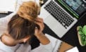 Stressed woman holding her head, staring down at her desk Take the COVID-19 business challenge