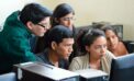 Students looking over shoulder of another student sitting at a computer National framework built for computer science curriculum