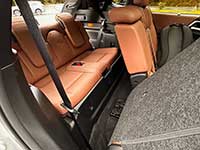2026-Outlander-PHEV-seating - Humboldt Voice Cargo area of a car with orange-brown leather rear seats folded down, gray carpeting, and a visible seat belt.